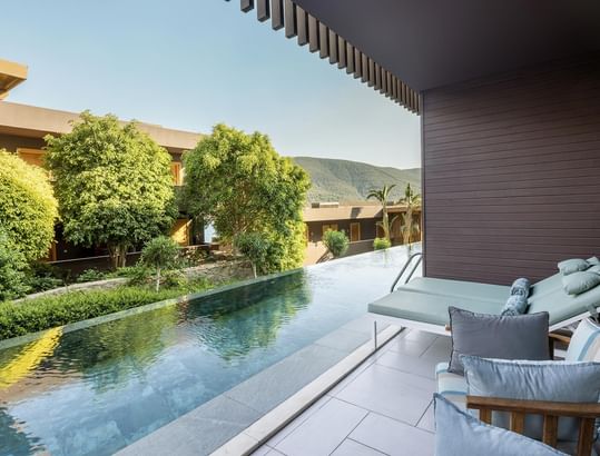 Swim-up Superior Room's pool, lounge chairs, and garden view at Titanic Luxury Collection Bodrum.
