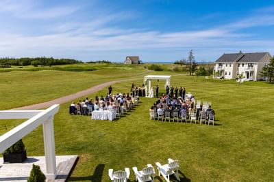 Outdoor wedding ceremony on a large green lawn overlooking the ocean at Rodd Crowbush Golf & Beach Resort