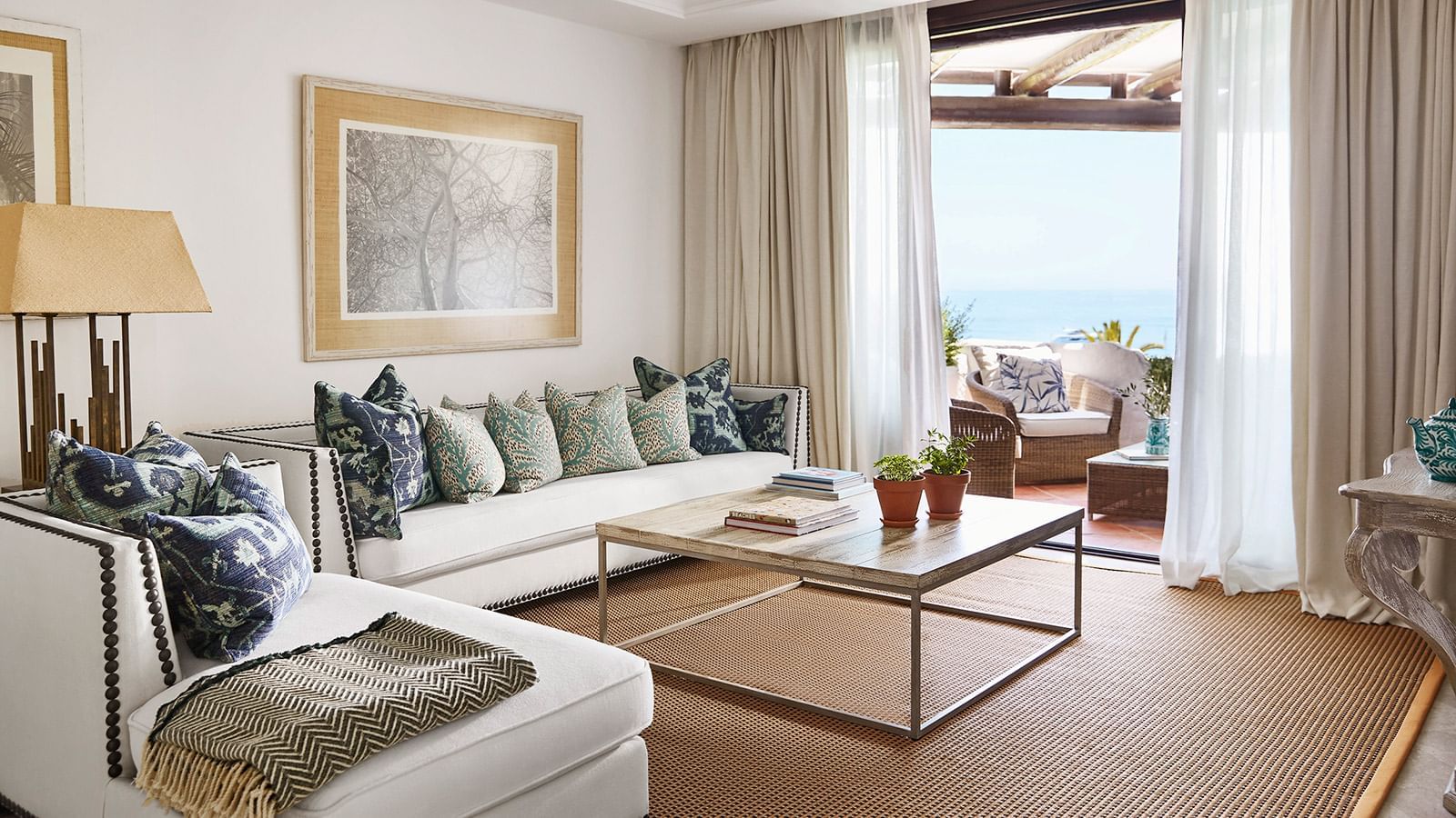 Royal Beach Suite living room with a metal-framed coffee table, sofa, & a terrace with a sea view at Marbella Club