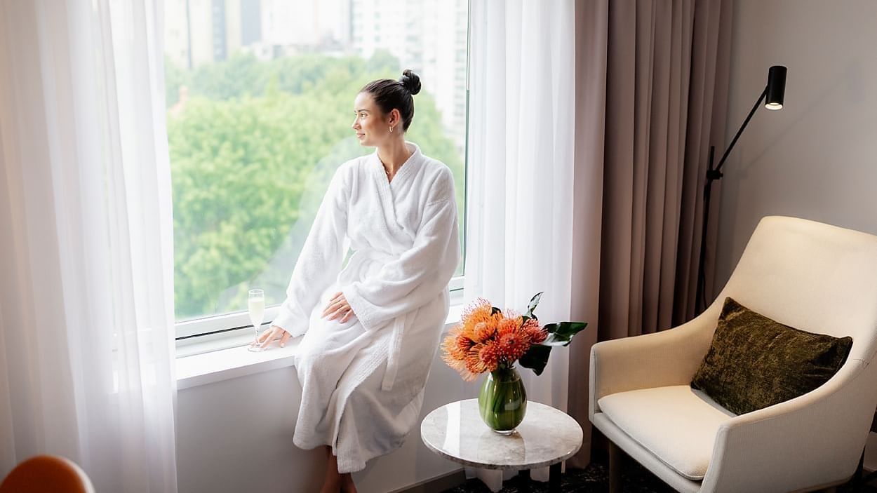 Lady enjoying the city view from a room at Novotel Darling Square