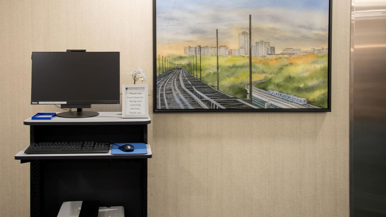Desktop computer setup with a scenic painting in the background.