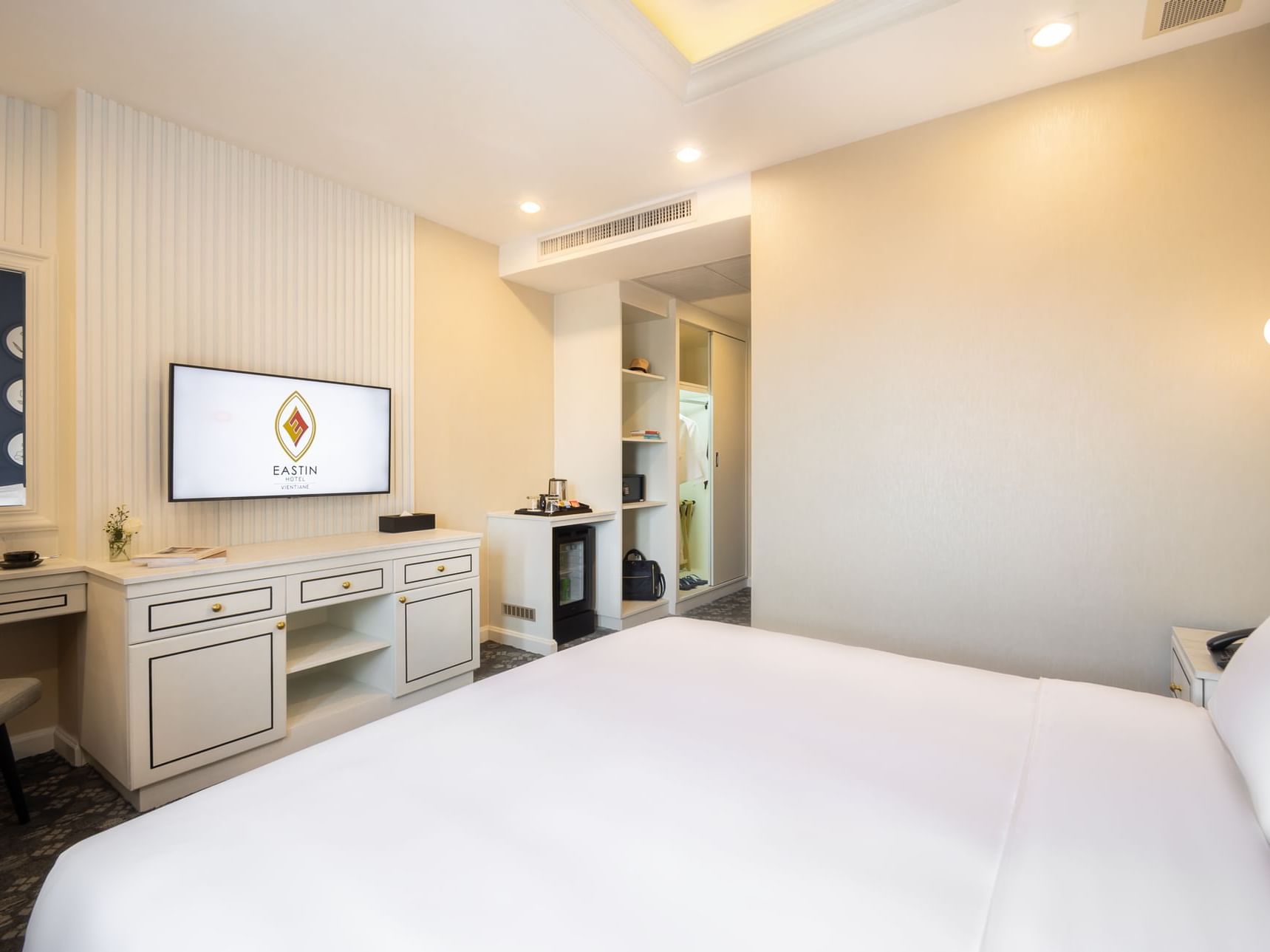 Comfy bed with TV area in Superior Room at Eastin Hotels
