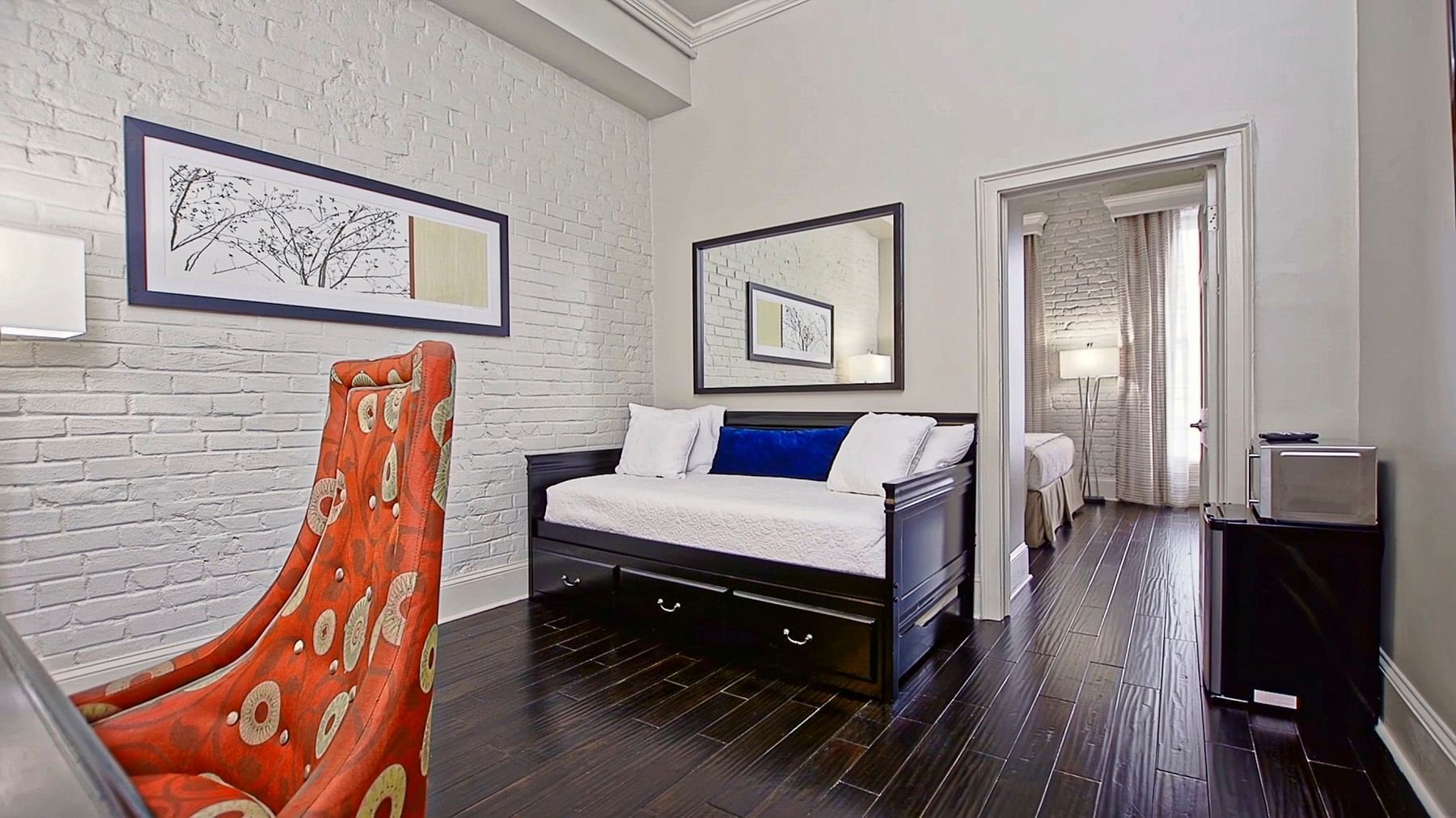 A hotel room with a bed, chair, and refrigerator