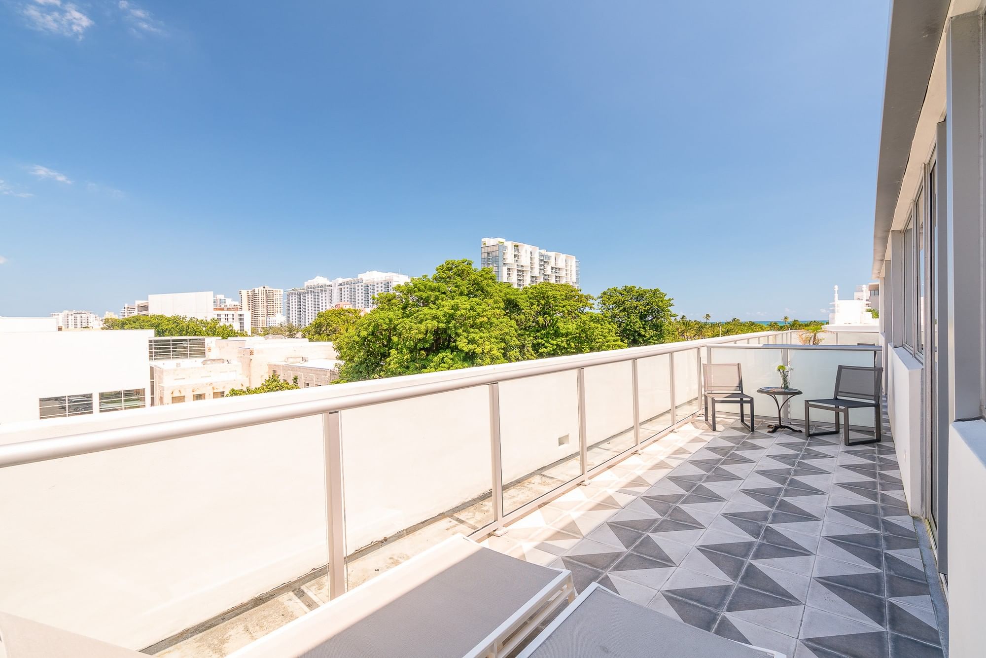A balcony with a railing, two chairs, and a small table overlooking the city.