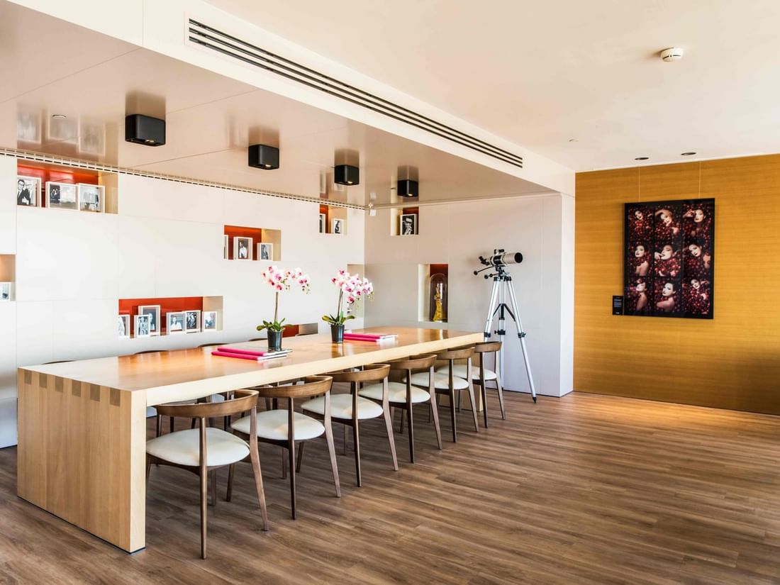 Panorama Lounge featuring a long wooden table with seating, and hanging art at The Hotels Brussels