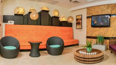 Sala de estar con sofá, muebles de ratán, lámparas colgantes y televisor de pared en el lobby del hotel The Beach House de Panamá
