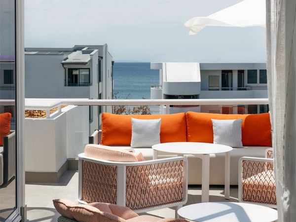 Ocean view balcony at Elysium Noosa with an orange sofa and woven chairs surrounding round tables under a white umbrella