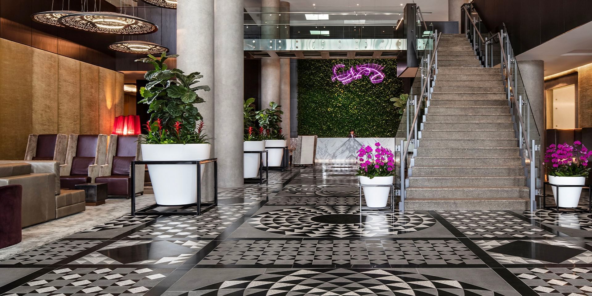 Lobby with geometric floor design, stairs, and decorative plants at Hotel X Toronto