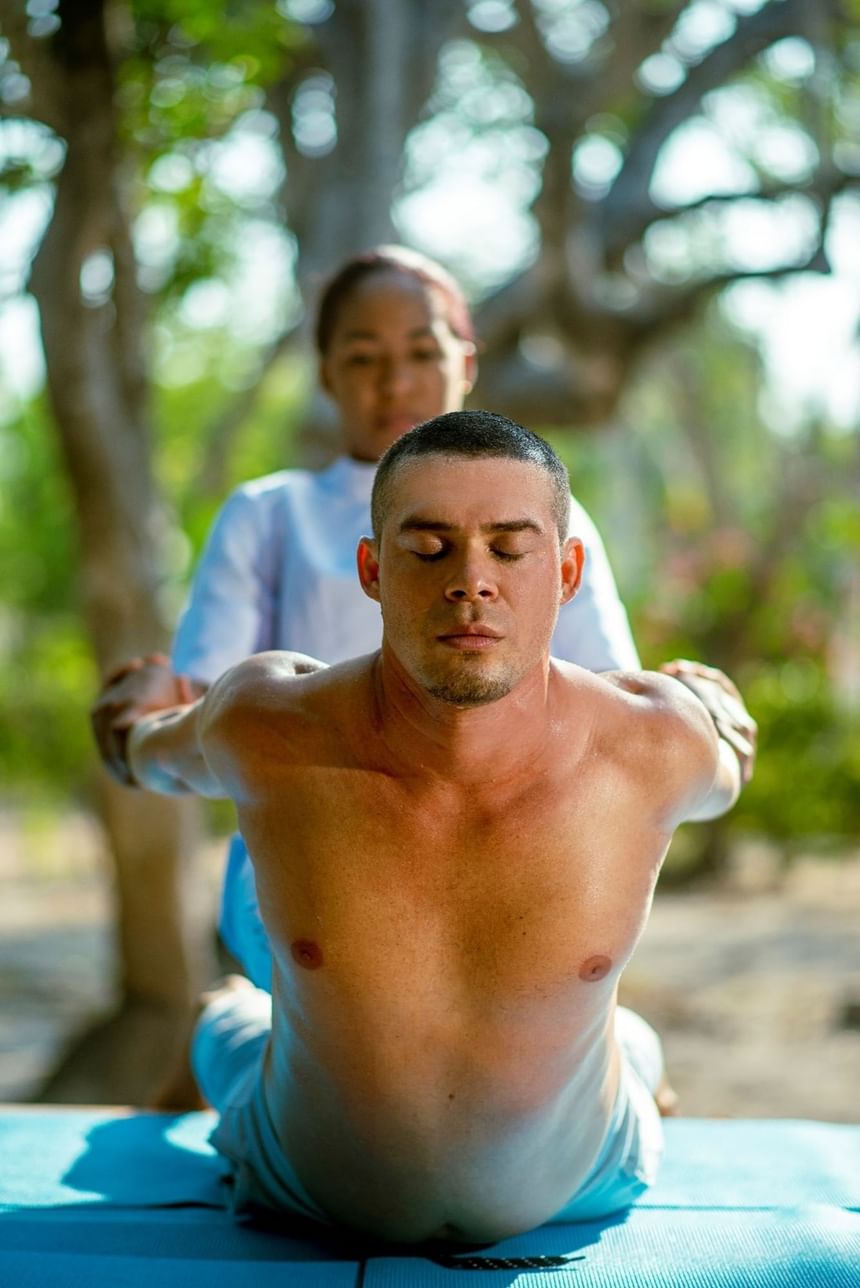 A man doing yoga with a woman's guidance at Hotel Isla Del Encanto