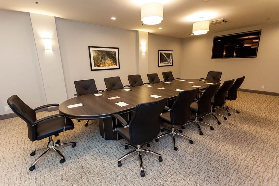 Executive chairs by a dark wood table under warm wall sconces in Encore Room at Warwick San Francisco