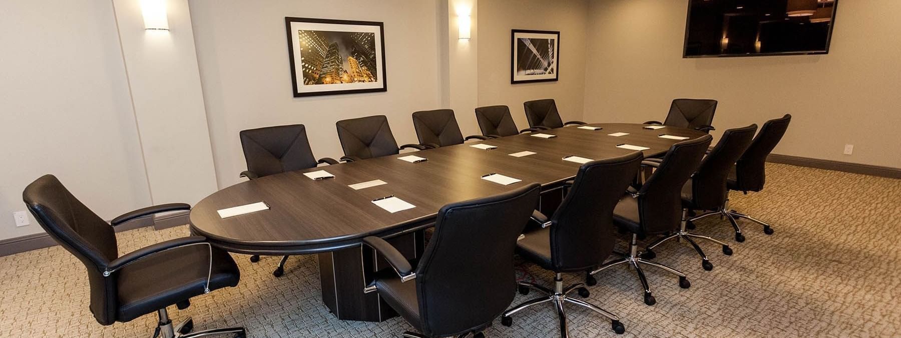 Executive chairs by a dark wood table under warm wall sconces in Encore Room at Warwick San Francisco
