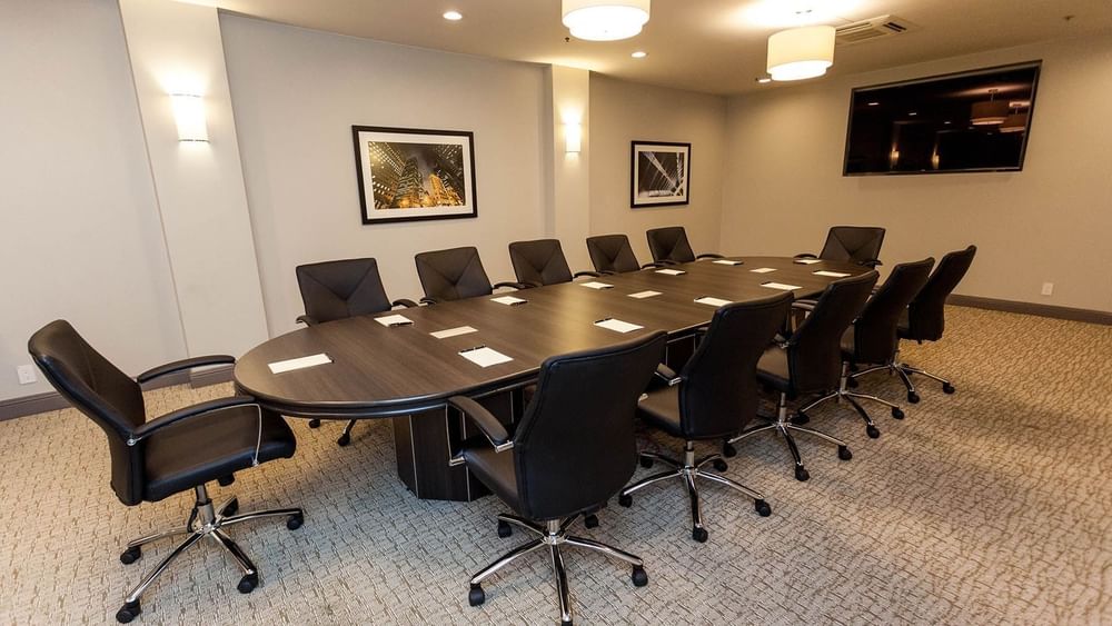 Executive chairs by a dark wood table under warm wall sconces in Encore Room at Warwick San Francisco