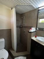 Tiled walk-in shower by a white toilet and vanity under a rectangular mirror at Warwick Hotels & Resorts