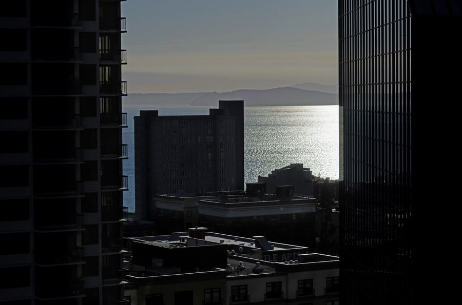 Sunlight reflecting on the water by city buildings and distant hills near Warwick Seattle