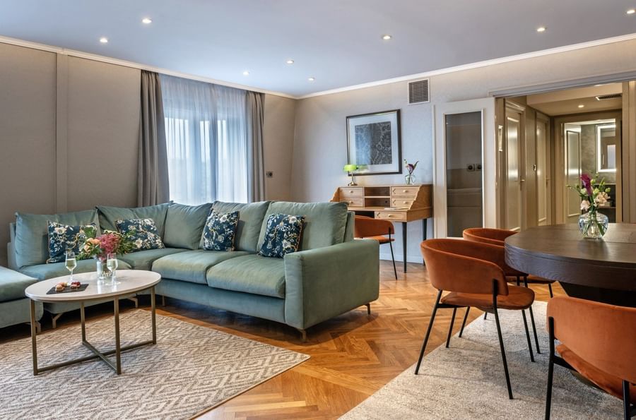 Living room scene with a cozy sofa, dining table, and work desk in the Privilege Suite at Warwick Reine Astrid - Lyon