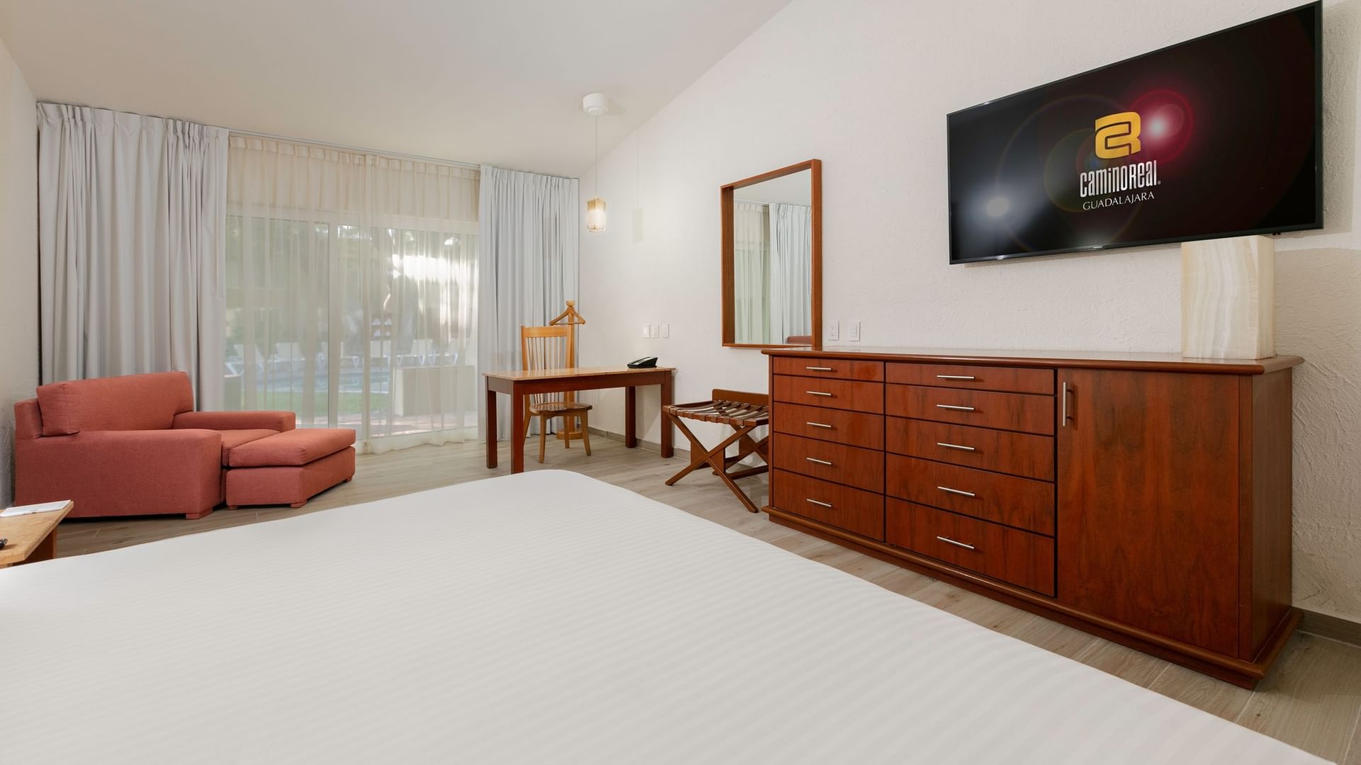 King Real Suite with a large bed, wooden dresser, and balcony view at Camino Real Guadalajara in Zapopan