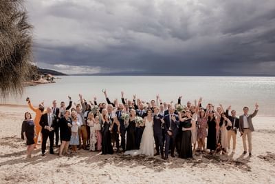 The wedding party posing on the Beach on a sunny day at Freycinet Lodge
