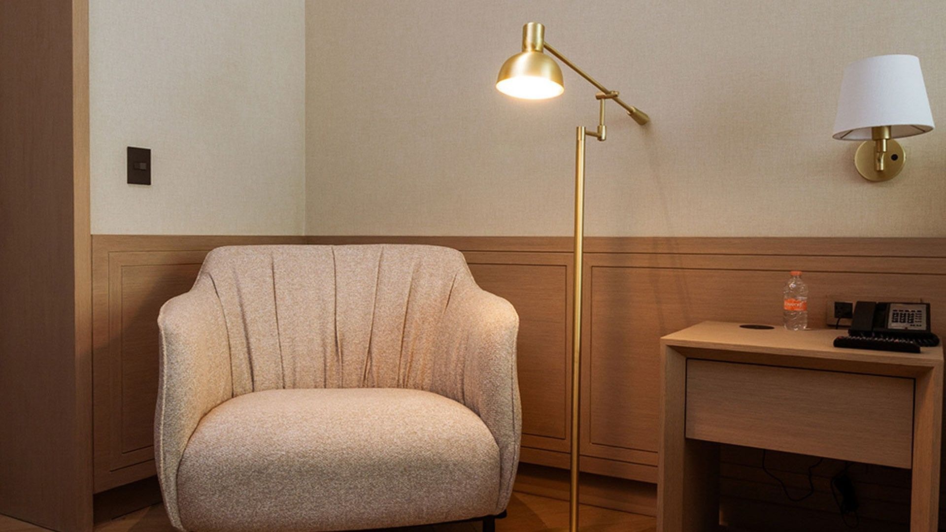 King Superior Viceroys Suite seating area with a beige armchair and a gold floor reading lamp at Camino Real Polanco Mexico