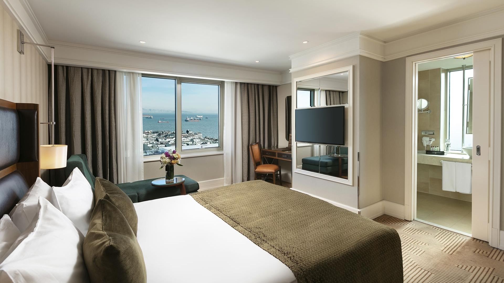 Titanic Port Bakırköy’de, geniş pencerelere, deniz manzarasına, king-size yatağa, çalışma masasına, koltuğa ve ferah bir banyoya sahip Deluxe oda.