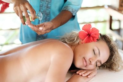 Massage therapist pouring oil on hands for a back massage in Spa at Musket Cove Island Resort & Marina