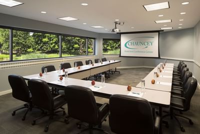 Modern conference room with U-shaped table setup, black chairs, and projection screen at Aramark Chauncey Conference Center