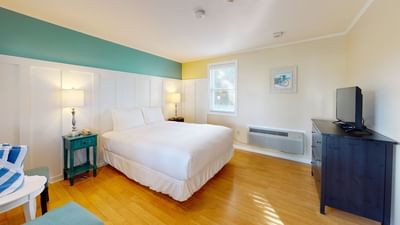 TV-facing bed with table lamp and wooden floors in One Queen at Breezeway Boutique Hotel