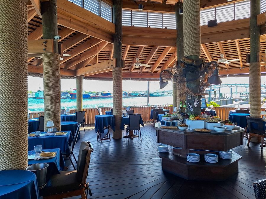 Round buffet table with fresh food by dining tables in Edgewater Grill at Warwick Paradise Island Bahamas