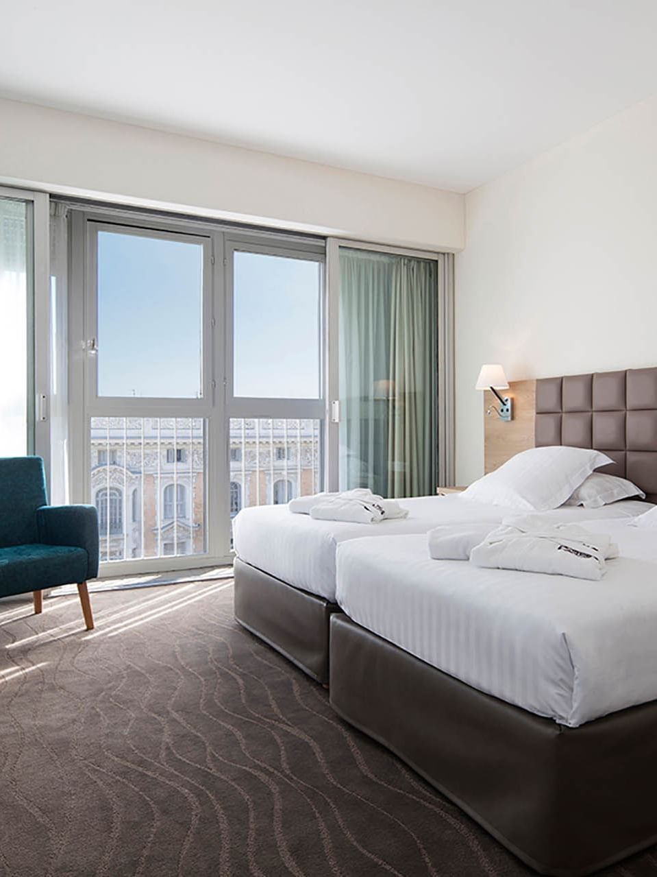 Suites with twin beds and soft robes, featuring a private balcony access and city views from the Splendid Hotel & Spa Nice