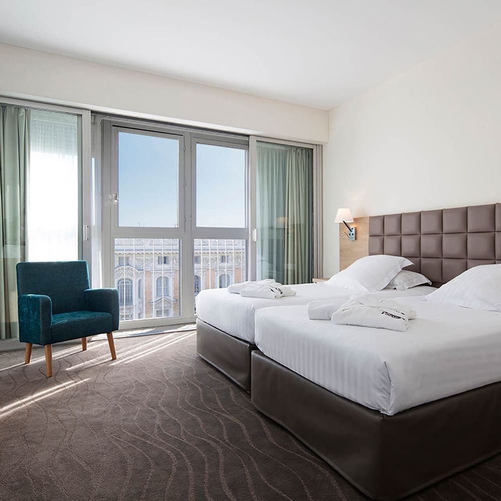 Suites with twin beds and soft robes, featuring a private balcony access and city views from the Splendid Hotel & Spa Nice