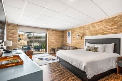 Junior Suite King at The Riverwalk Plaza Hotel with a bed, workstation, seating area, brick walls, and a balcony view