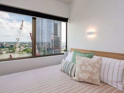 Cozy bed with floral pillows in a modern room at UniLodge Brisbane City.