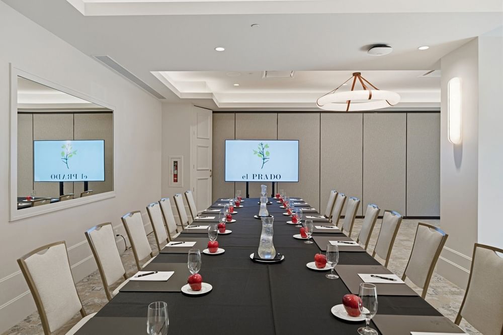 meeting room set up at el PRADO with a screen at the end of the table reading el PRADO with a yellow flower