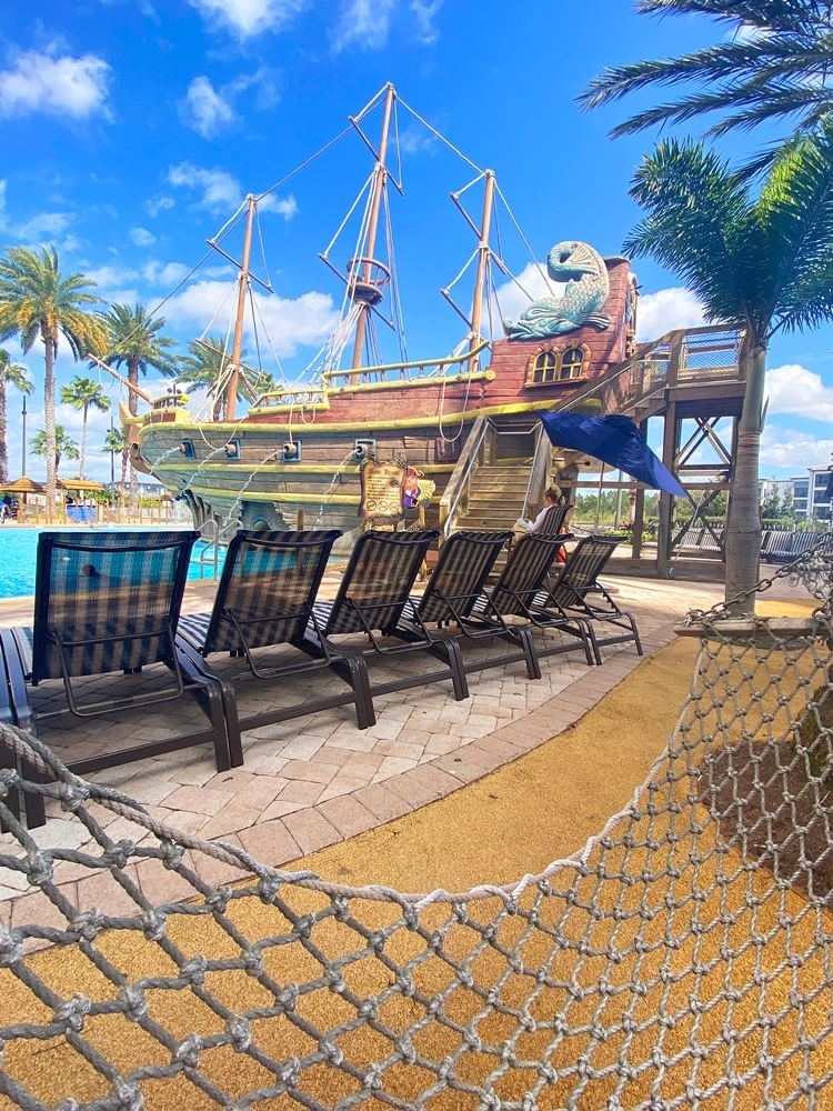 a pool with lounge chairs and a pirate ship