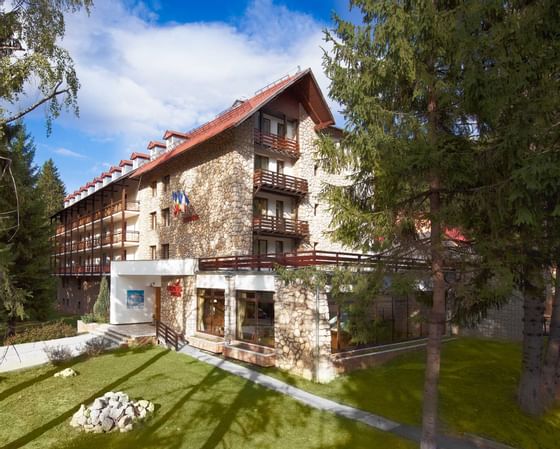 An exterior view of Ana Hotels Poiana with green lawn