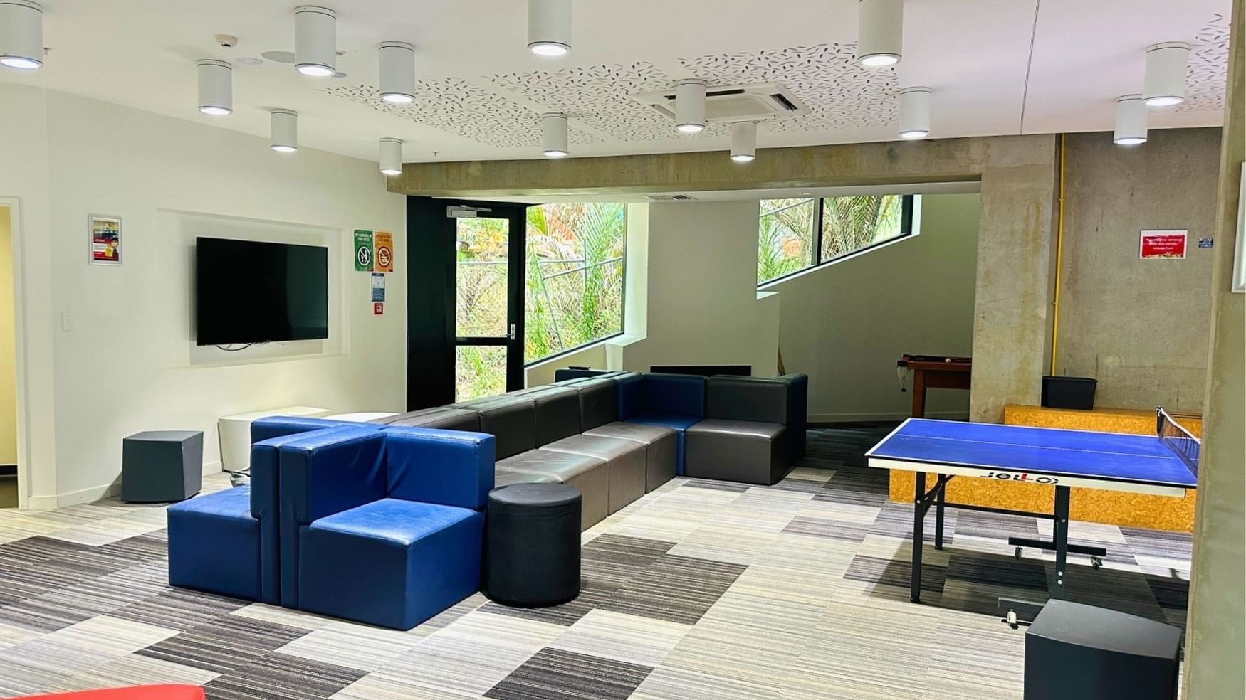 Comfortable lounge area with a ping pong table and large TV at UniLodge Auckland City.