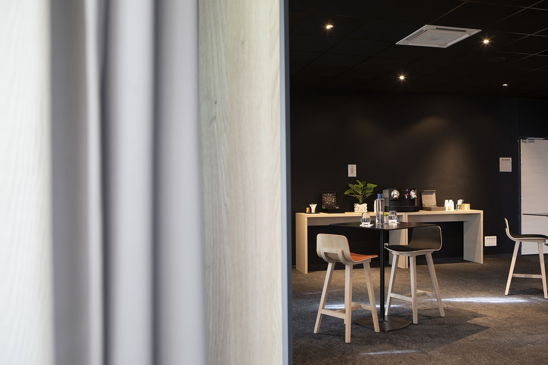 Salle de conférence sombre avec table et chaises en bois à Oceania Paris Roissy CDG