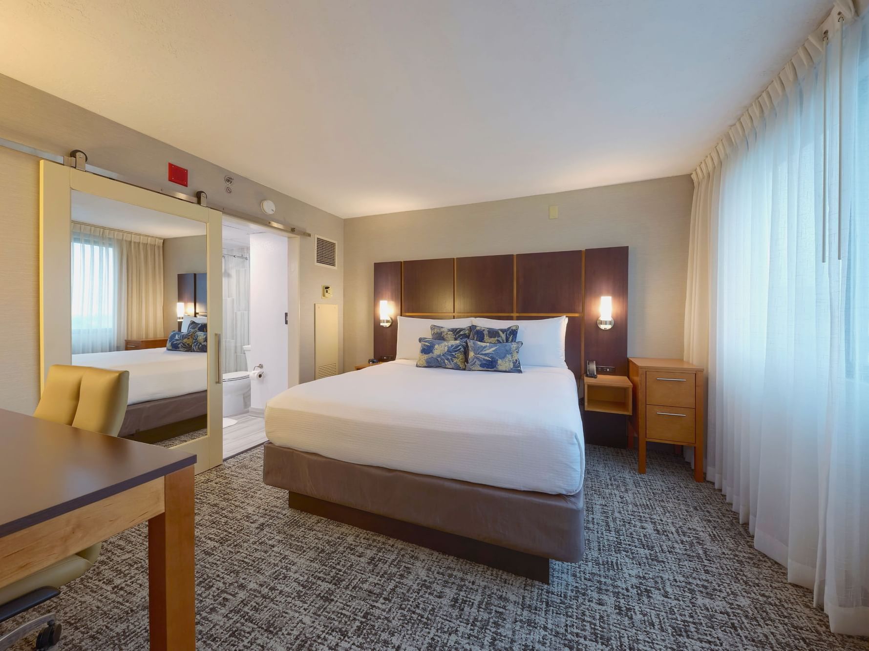 VIP Business Suite hotel room with a bed, desk, chair, and a bathroom at the NCED Hotel and Conference Center.