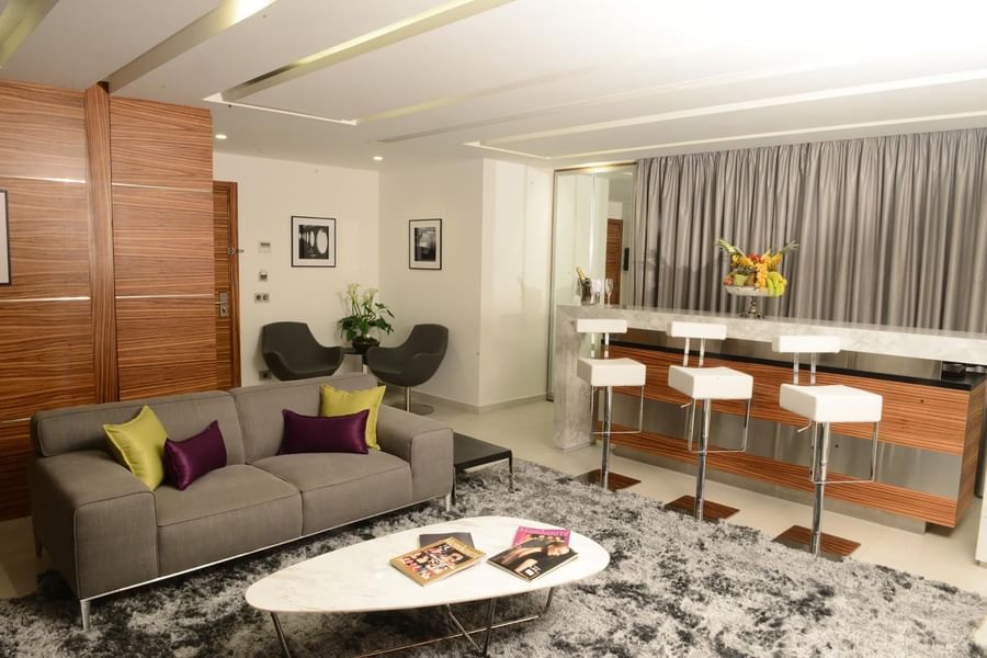 Grey sofa by a marble table under white bar stools near a wooden wall in Executive Suite at Warwick Stone 55 - Beirut