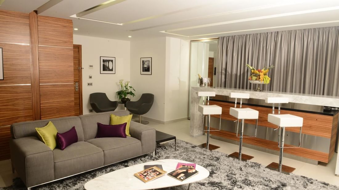 Grey sofa by a marble table under white bar stools near a wooden wall in Executive Suite at Warwick Stone 55 - Beirut