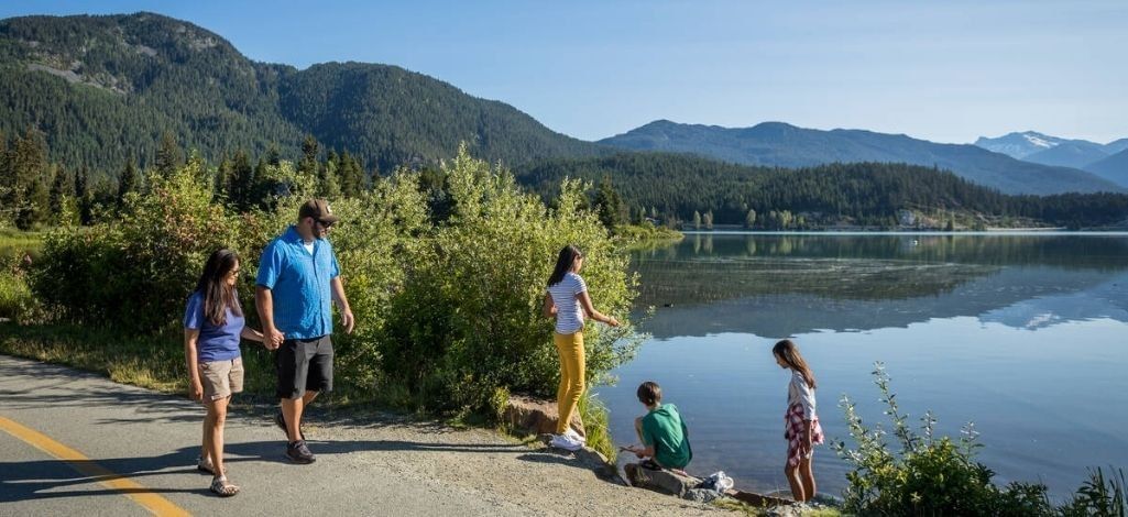 Family walking beside Green Lake in Whistler with mountain views