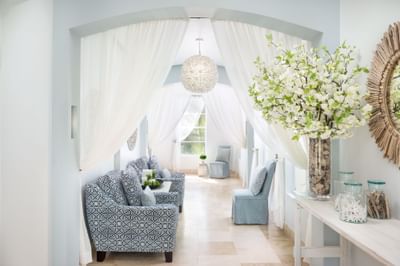 Bright corridor with plush chairs, a floral arrangement, and soft lighting in Drift Spa at Windsong Resort On The Reef