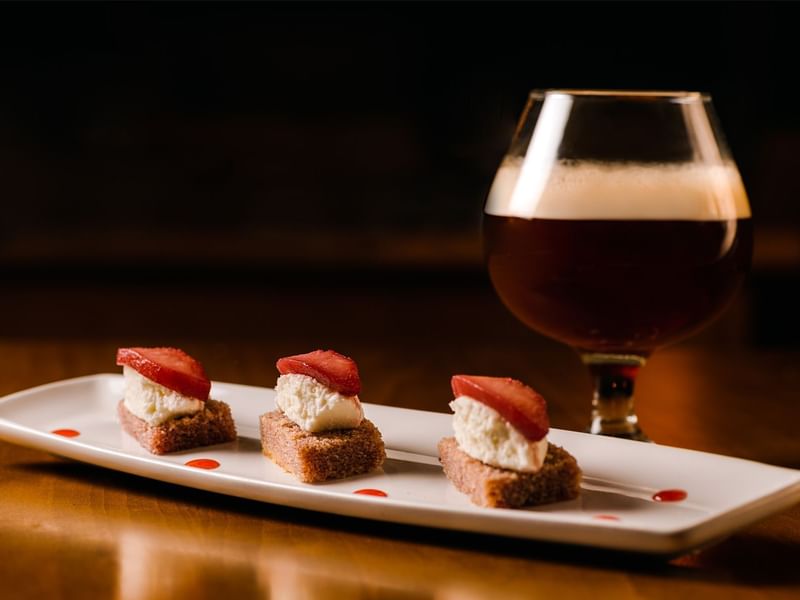 Gourmet dessert with strawberries and cream, paired with a glass of dark beer near Fiesta Americana