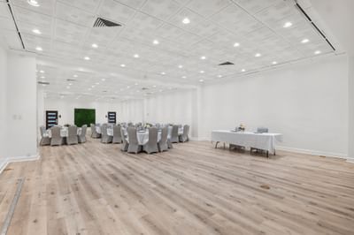 Spacious, well-lit ballroom at The Riverwalk Plaza Hotel with round tables, chairs, a head table, and a green wall accent