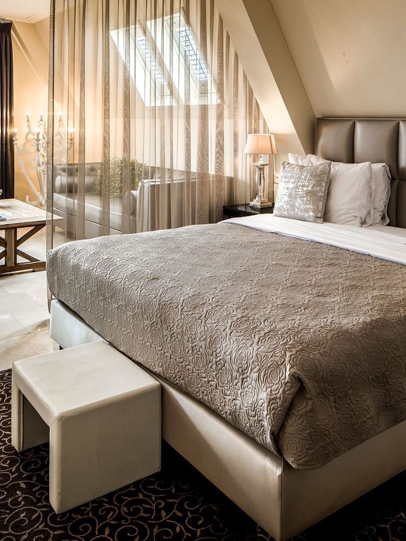 Cozy lounge area with plush seating and an ottoman by the bed in the luxurious suite at Warwick Hotels & Resorts