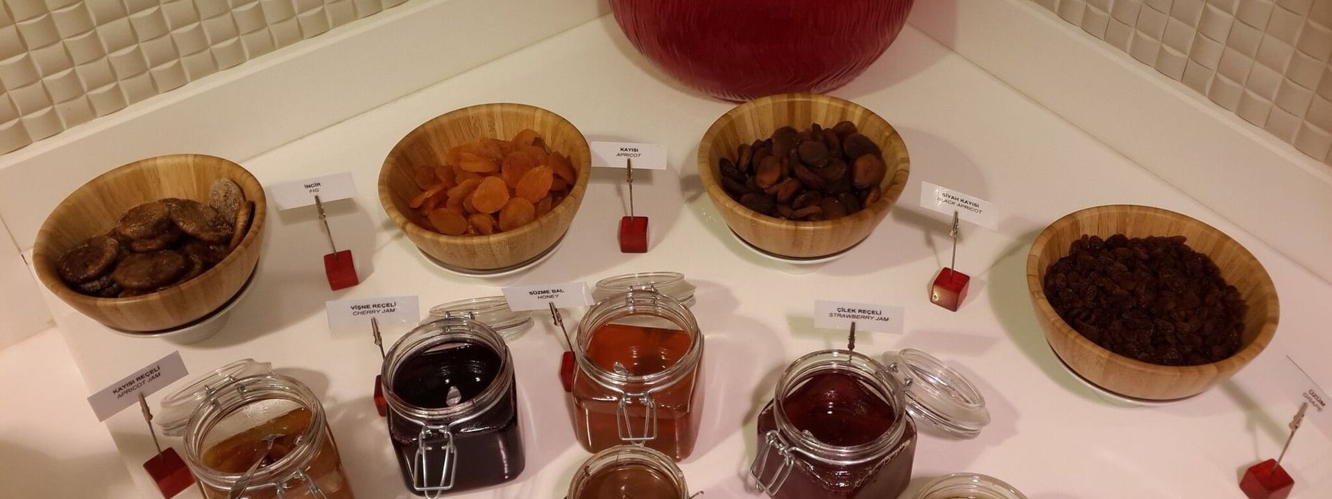 Breakfast & In-Room Dining with Jars of jam by wooden bowls of dried fruit surrounding a red vase at Warwick Ankara