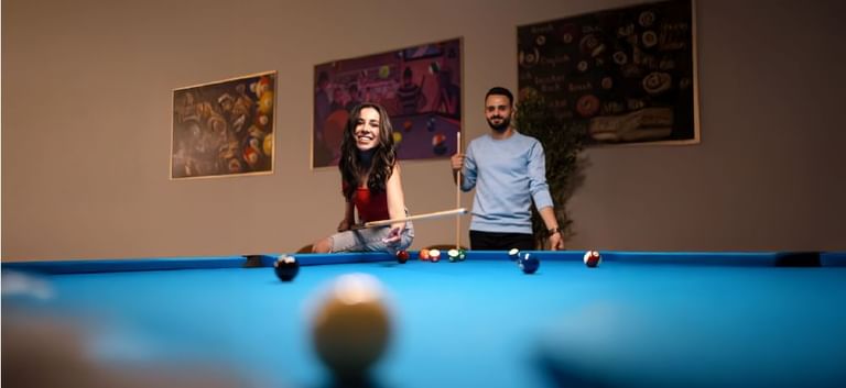 Smiling couple enjoying a fun billiards game together in Level Up - Indoor Gaming Hub at DAMAC Maison Aykon City