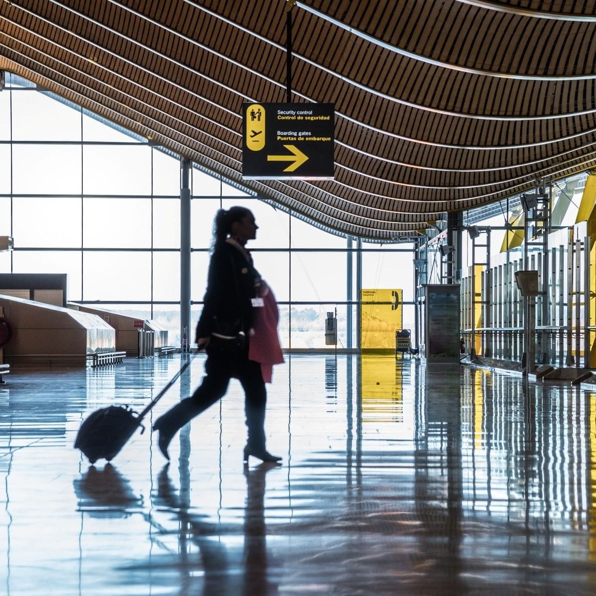 Mujer caminando con maleta en un aeropuerto moderno y luminoso.