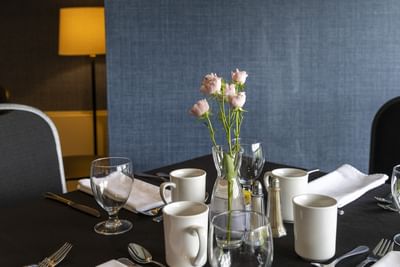 Pink roses in a glass vase with white coffee mugs at Rodd Brudenell River Resort,top-rated party rentals PEI