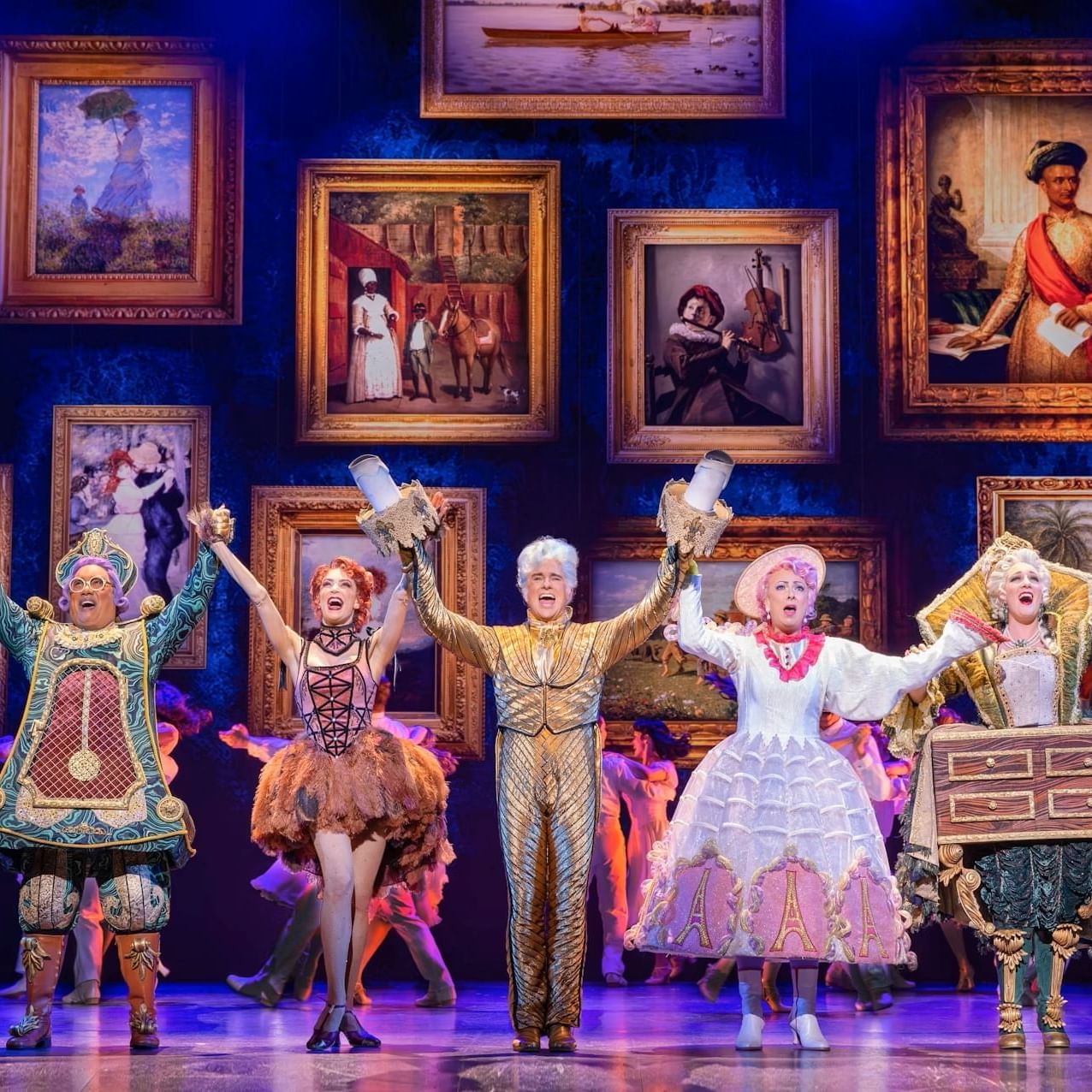 Cast of Disney’s Beauty and the Beast performing on stage in a grand, colourful scene with Belle and the enchanted objects.