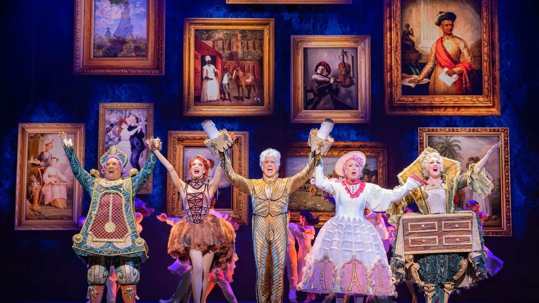 Cast of Disney’s Beauty and the Beast performing on stage in a grand, colourful scene with Belle and the enchanted objects.